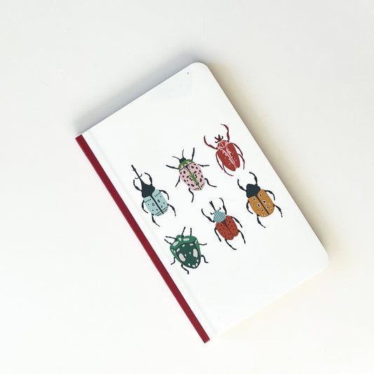 Libreta con dibujo de bichos de colores y lomo rojo