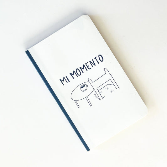 Foto de libreta con dibujo de mi momento, una mesa con café y una silla